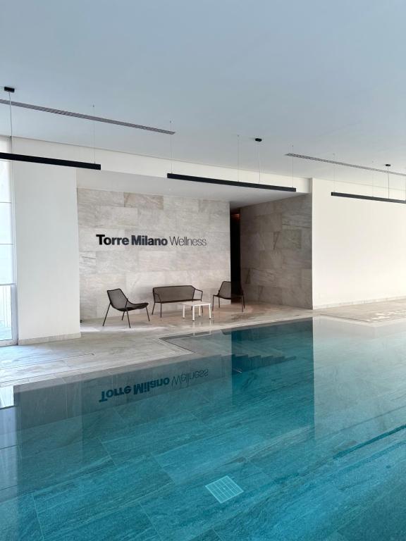 una piscina con 2 sillas y una mesa en un edificio en Torre Milano - Luxury modern flat, en Milán