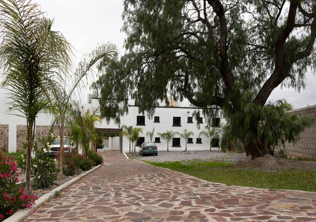 eine Backsteinstraße mit einem Baum und einem weißen Gebäude in der Unterkunft Hotel & Temazcal Hacienda Maxthá in Huichapan