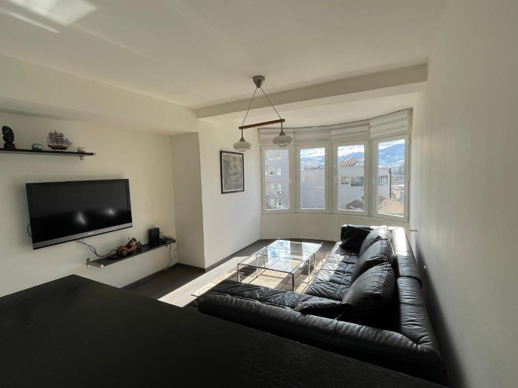 uma sala de estar com um sofá de couro e uma televisão de ecrã plano em SleepInNP em Novi Pazar