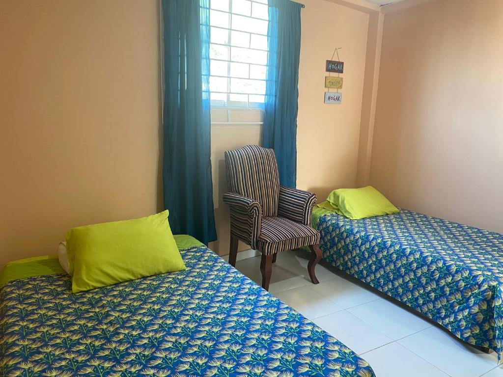 a room with two beds and a chair and a window at Habitacion en Cartagena in Cartagena de Indias