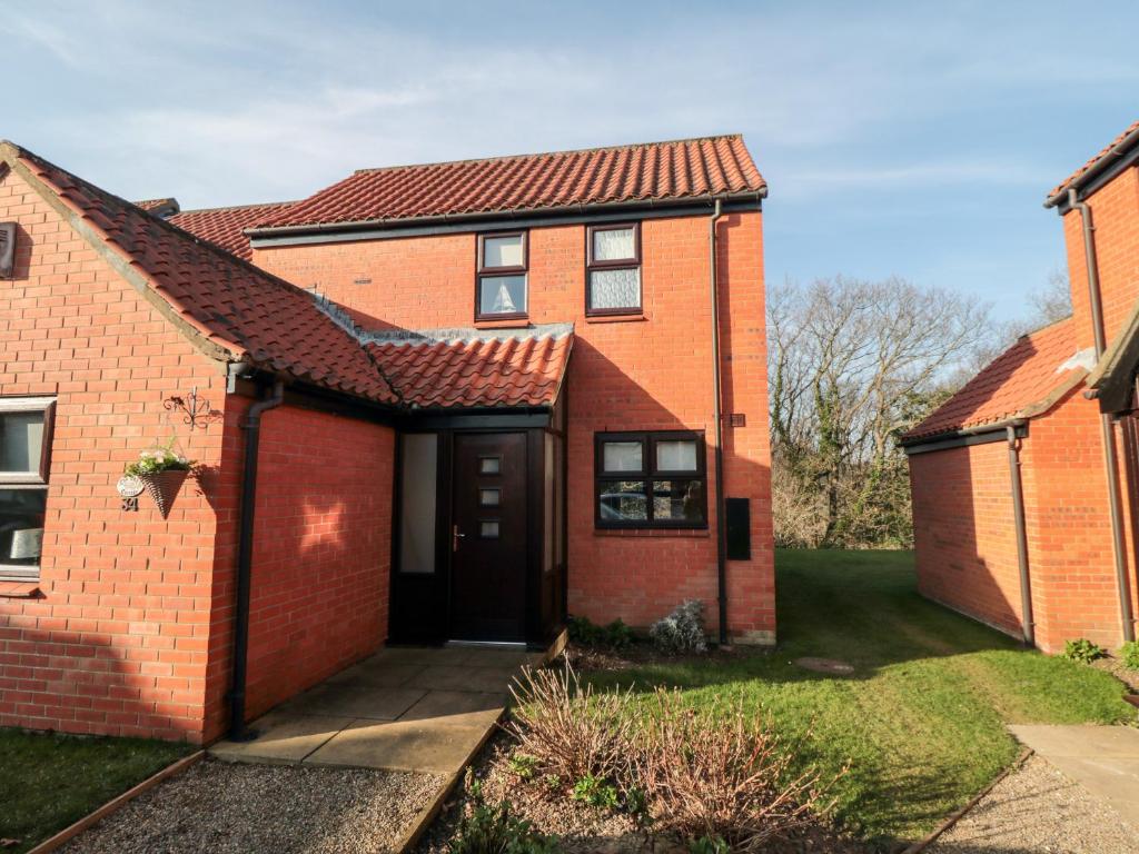 a red brick house with a black door at Cha Cha's Cottage in Whitby
