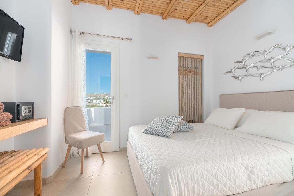 ein weißes Schlafzimmer mit einem Bett und einem Stuhl in der Unterkunft Le Ciel Suites & Villas in Mykonos Stadt