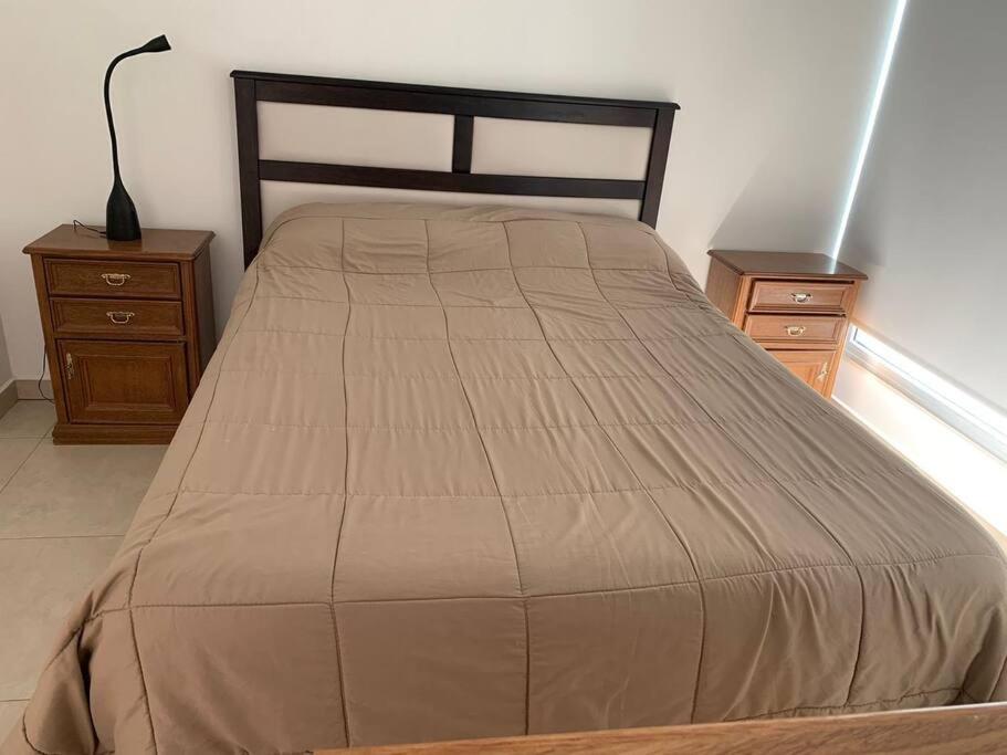 1 cama en un dormitorio con 2 mesitas de noche y lámpara en Hermoso depto en excelente ubicacion en Puerto Madryn