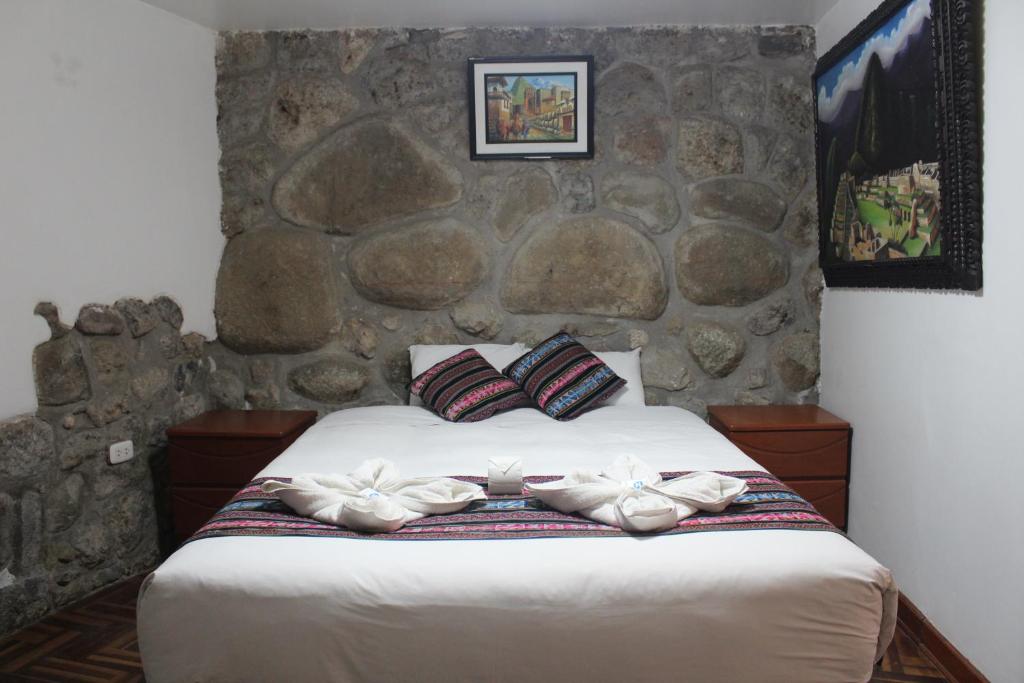 - une chambre avec un lit et un mur en pierre dans l'établissement Hostal Turistico ILLAPA CUSCO 119, à Cusco