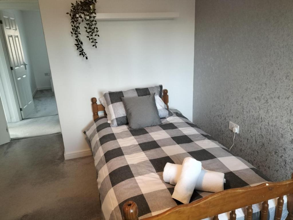 a bedroom with a bed with a checkered blanket at St Martins House Birmingham Near the NEC, Jaguar Land Rover, HS2, Resorts World, Bear Grylls Centre and Birmingham Airport, with garage and free allocated parking, perfect for contractors and families in Kingshurst
