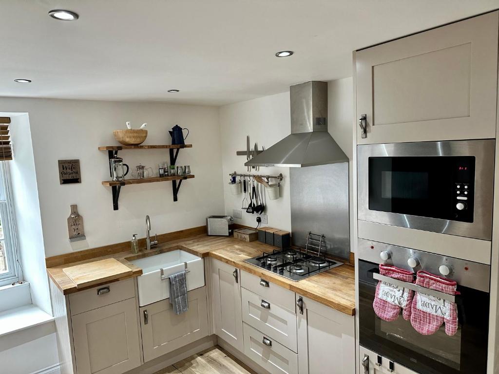 a kitchen with white cabinets and a stove top oven at Brechin Townhouse - Cathedral View in Brechin