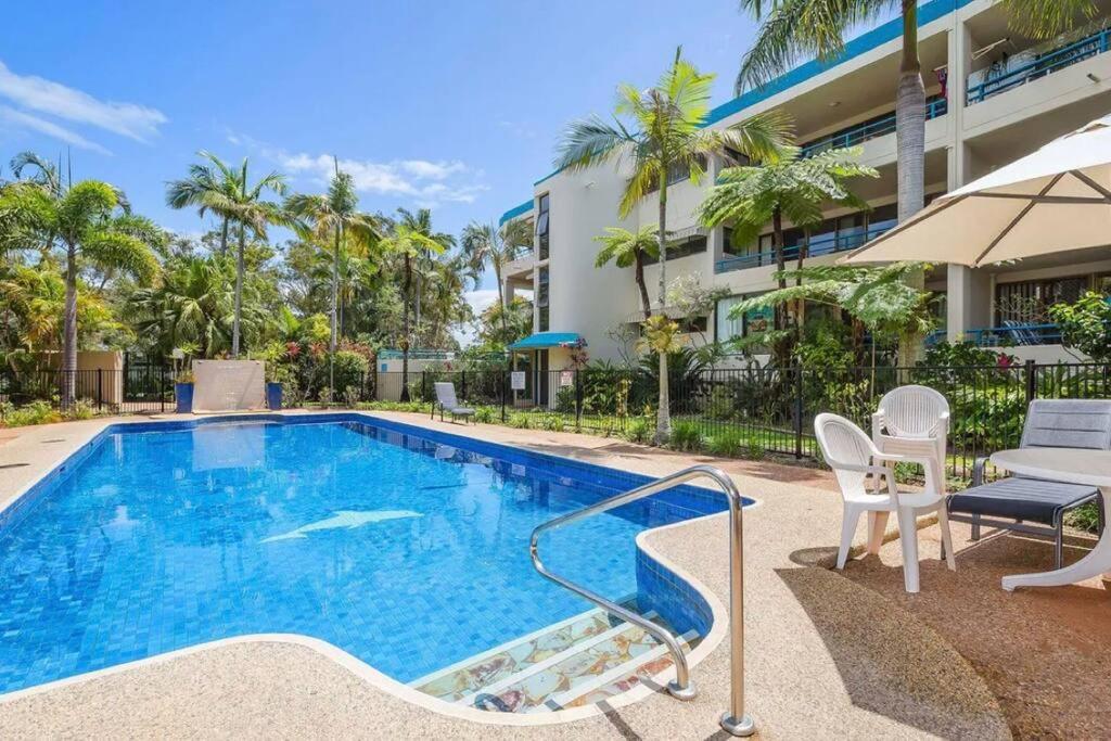 a swimming pool with chairs and a building at Our Beach House in Bribie Island in Bongaree