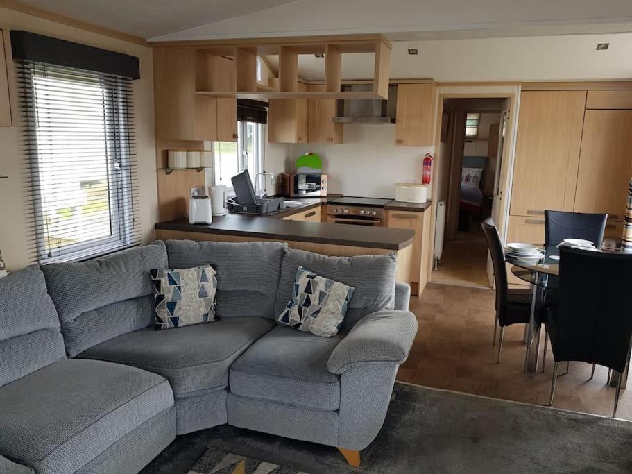 a living room with a couch and a kitchen at Home from Home cosy caravan in Bembridge