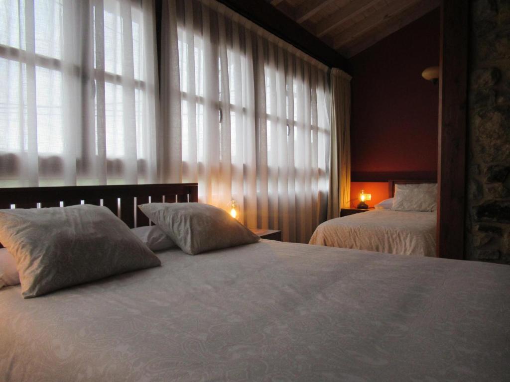 a bedroom with two beds and a large window at Casa Rosales ( Posada Rural) in Cardes