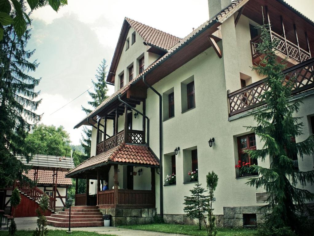 ein großes weißes Haus mit einem Balkon und einer Treppe in der Unterkunft Penzion U Ráztoky in Rusava