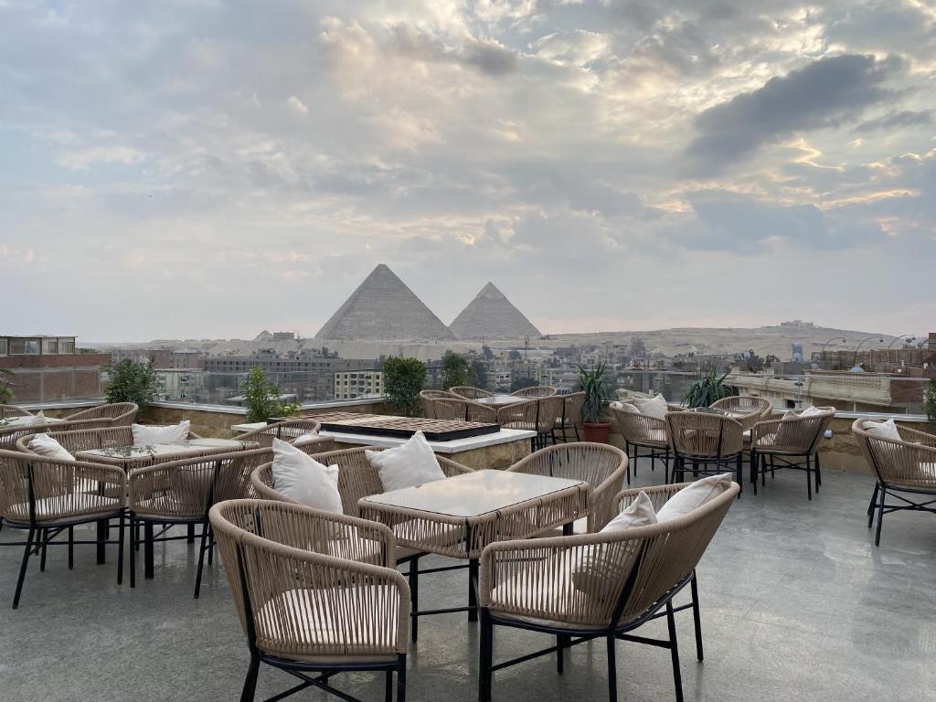 a patio with tables and chairs with pyramids in the background at The View Delta Hotel in Cairo