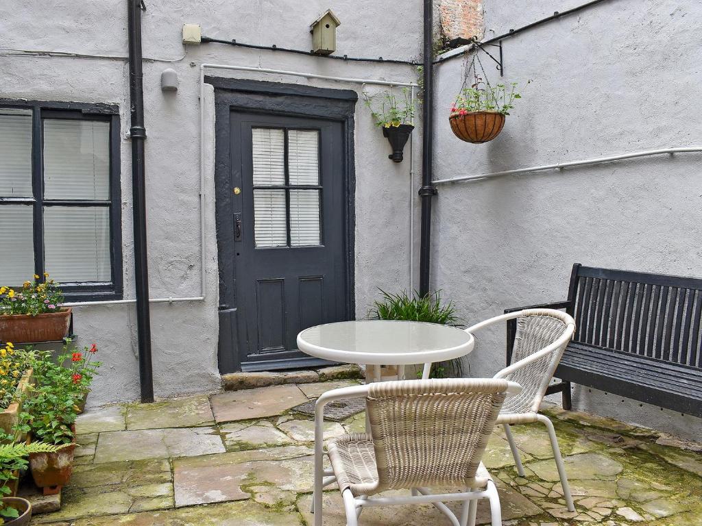 a patio with a table and chairs and a door at Hogwood Cottage in Knaresborough
