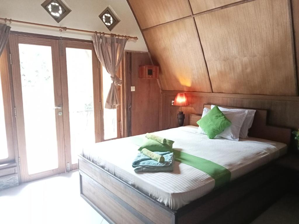 Un dormitorio con una cama con almohadas verdes. en Meno Smile Cottages, en Gili Meno