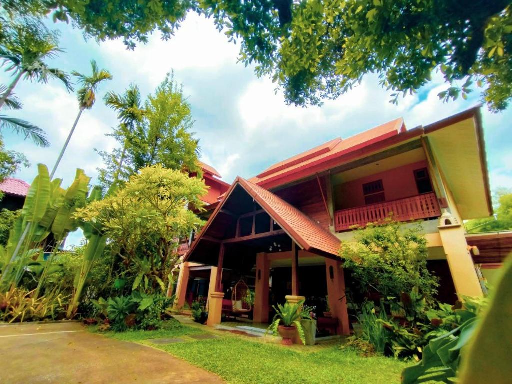 una casa con techo rojo y algunos árboles en AuangKham Resort en Lampang