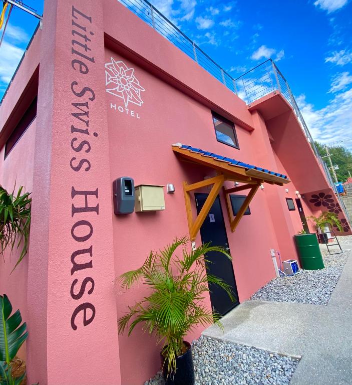 a pink building with a sign on it at Hotel Little Swiss House in Motobu
