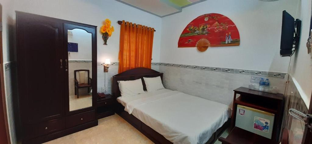 een kleine slaapkamer met een bed en een spiegel bij Huynh Lac Can Tho Hotel in Can Tho