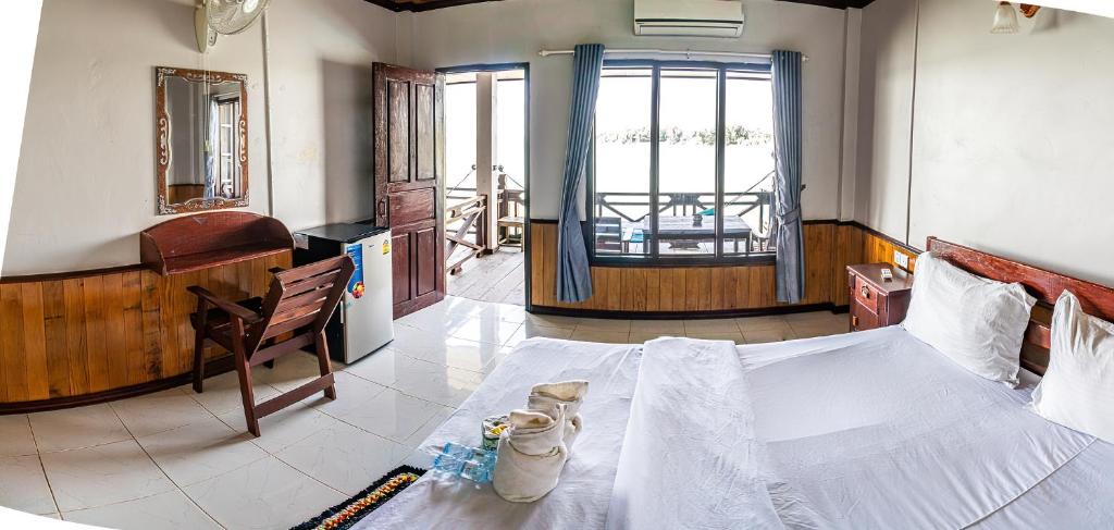 Schlafzimmer mit einem Bett, einem Schreibtisch und einem Fenster in der Unterkunft DON DET Souksan Sunset Guesthouse and The Xisland Riverview Studio in Ban Donsôm Tai