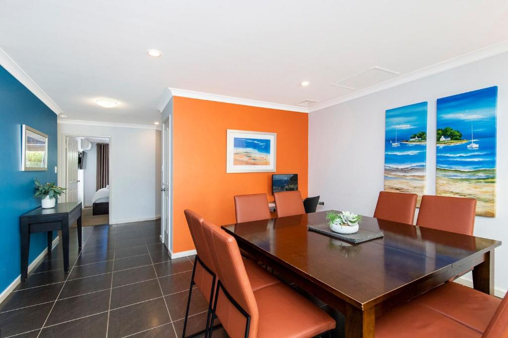an orange dining room with a wooden table and chairs at FiftyTwo at Cape View in Busselton