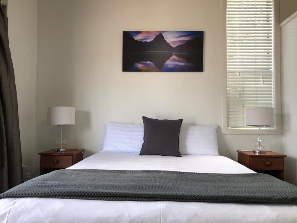 a bedroom with a large bed with two night stands at Rosetown Motel in Te Awamutu