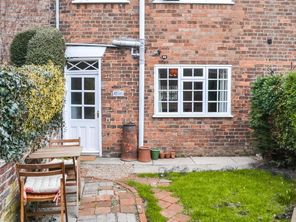 ein Backsteinhaus mit einer weißen Tür sowie einem Tisch und Stühlen in der Unterkunft Coopers Cottage in Louth