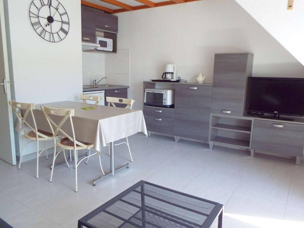 Il comprend une cuisine et une salle à manger avec une table et une télévision. dans l'établissement Duplex refait à neuf à Carnac - 3 chambres, balcon sud, parking, 300m de la plage - FR-1-477-145, à Carnac