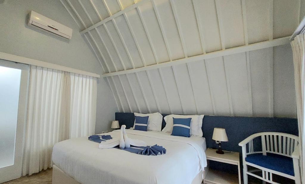 a bedroom with a large bed with blue and white pillows at Cosè Gili Beach Resort in Gili Trawangan