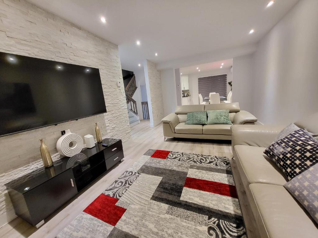 uma sala de estar com uma grande televisão na parede em 4 Bedrooms Beautiful Townhouse em Montreal