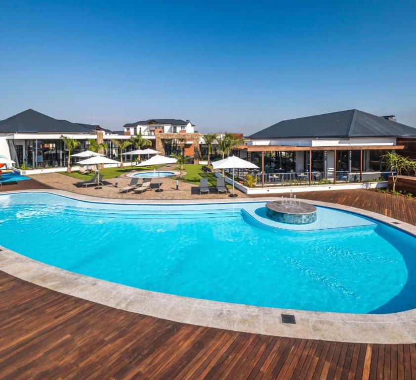 a large swimming pool in a resort with tables and umbrellas at BALLITO HILLS, 1 bedroom apartment in Ballito