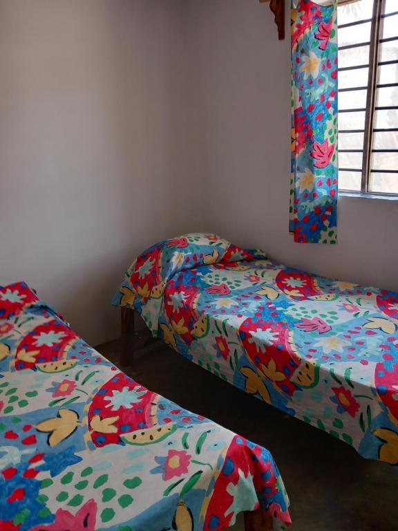 2 camas en una habitación con sábanas coloridas en Bibi Mrembo Guesthouse, en Pingwe