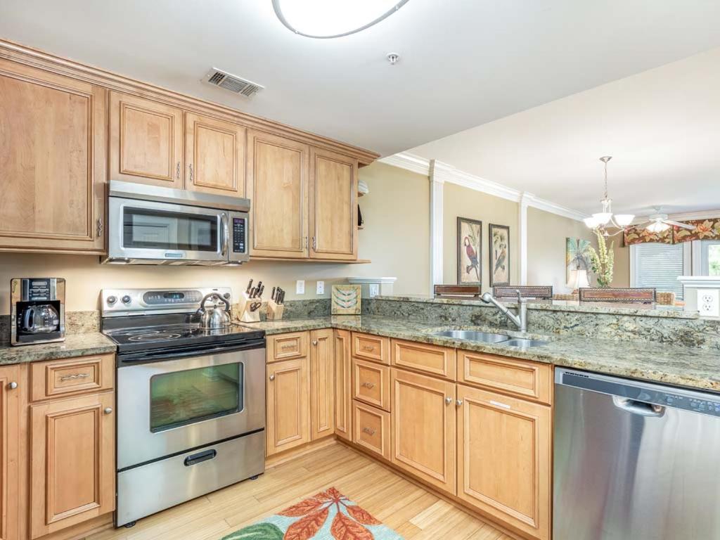 a kitchen with wooden cabinets and stainless steel appliances at Brass Rail 316 in Tybee Island