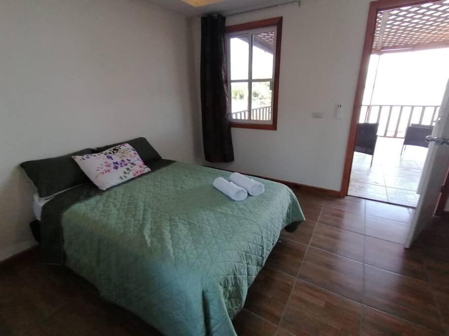 a bedroom with a bed with a green comforter at Cabaña Villa Sol in Tonalá