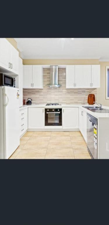 een keuken met witte kasten en een koelkast bij Private Room3 20 min CBD CITY Airport in Truganina