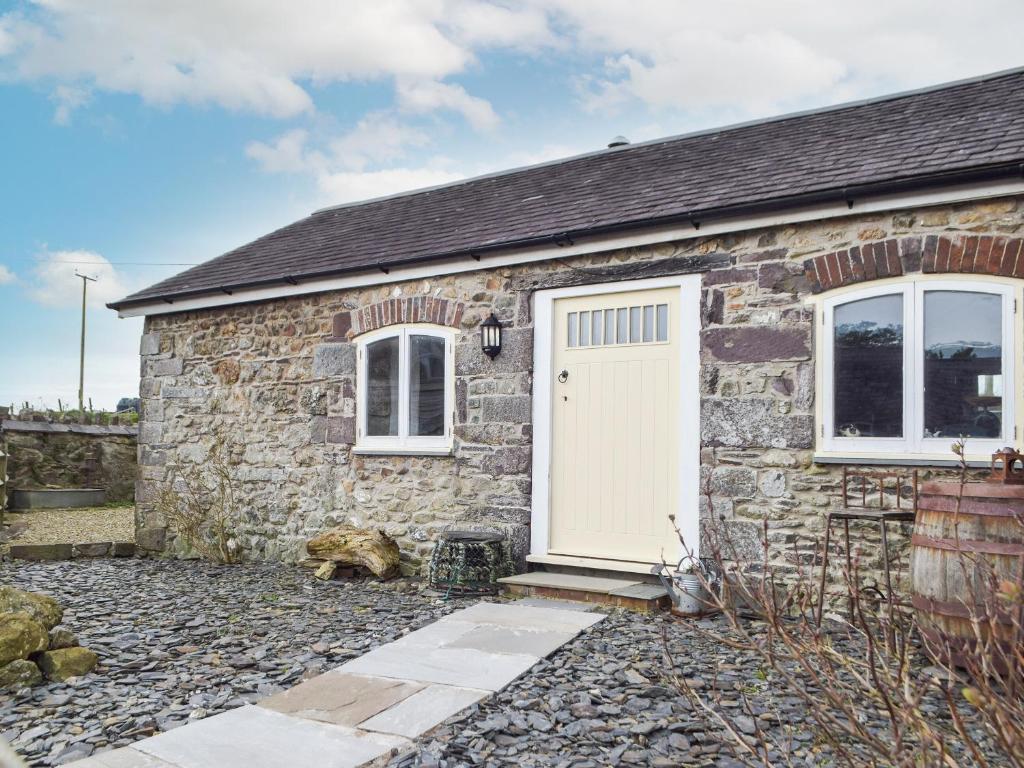 a stone cottage with a white door and windows at Pipistrelle Cottage - Uk34447 in Mathry