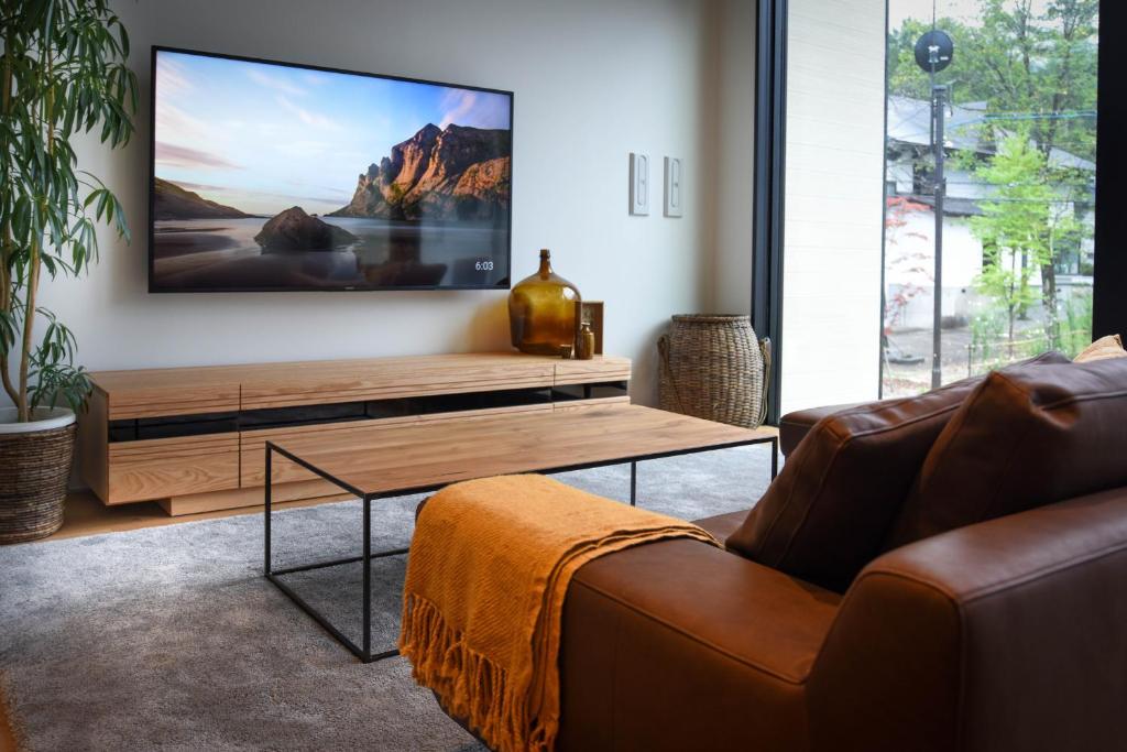 a living room with a couch and a flat screen tv at Prominence by The Hakuba Collection in Hakuba