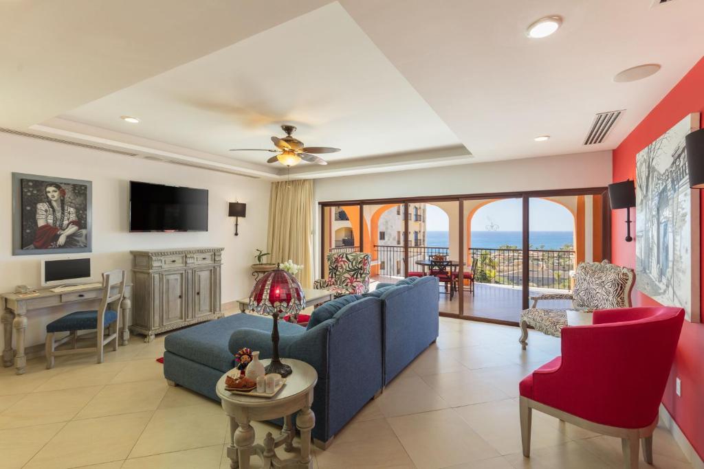 a living room with a blue couch and red chairs at Villas At Hacienda Encantada in Cabo San Lucas