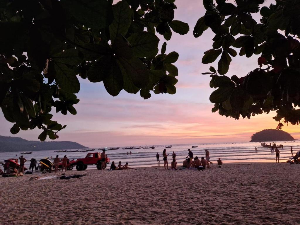 um grupo de pessoas em uma praia ao pôr do sol em San Antonio Beach Guesthouse & Restaurant em Praia de Kata