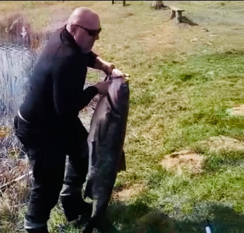 a man holding a fish in a body of water at Family Resort in Mostiska