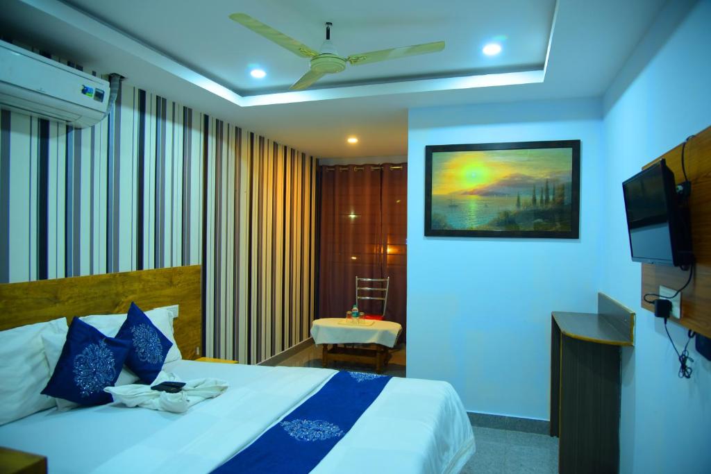 a hotel room with a bed and a television at Hotel Housefinch Residency in Bangalore