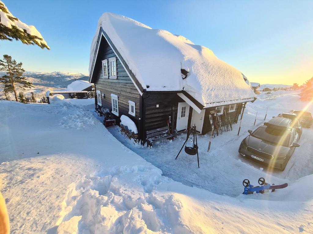 a snow covered house with a car parked next to it at Vrådal Panorama - Flott hytte på toppen in Sinnes