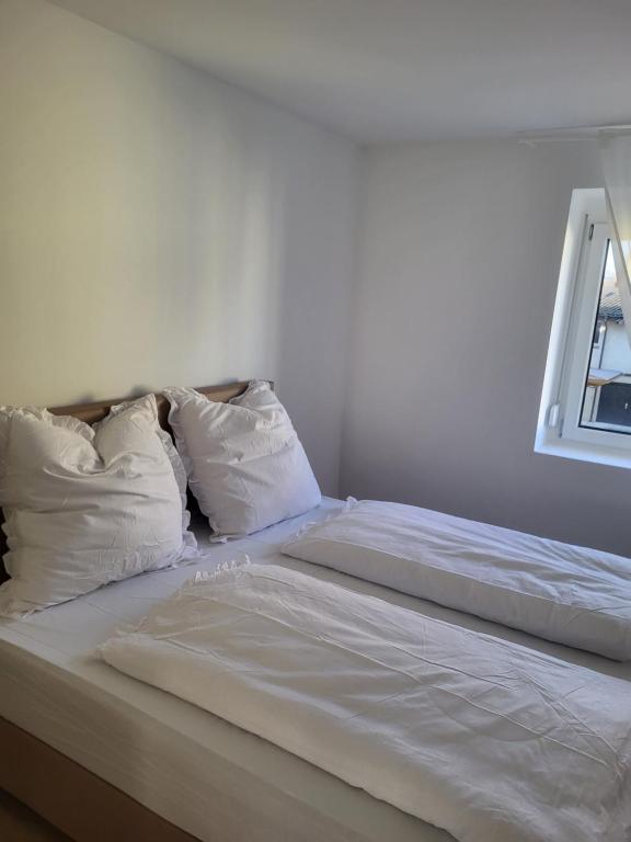 Apartment in Plankstadt في Plankstadt: سرير بملاءات ومخدات بيضاء بجانب نافذة