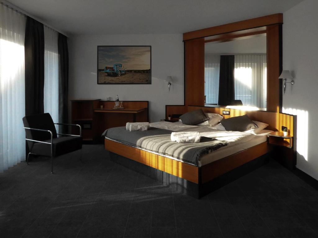 韋特海姆的住宿－Hotel am Malerwinkel，一间卧室配有一张带镜子和椅子的床