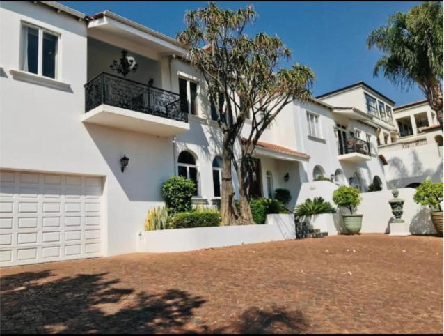 ein großes weißes Haus mit einem Balkon und einer Auffahrt in der Unterkunft Waterkloof Mansion Boutique Hotel in Pretoria