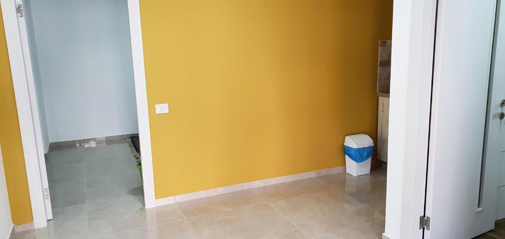 une chambre avec un mur jaune et une poubelle dans l'établissement במרכז הכפר, à Majdal Shams