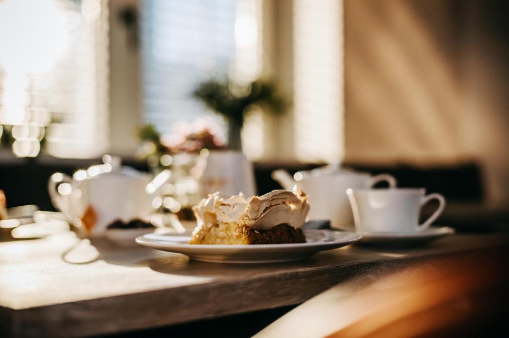 a piece of cake on a plate on a table with cups at Seaside 43 in Sankt Peter-Ording