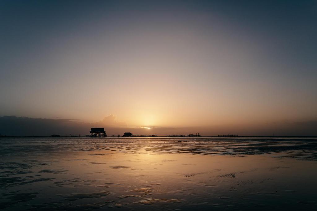 a sunset on the beach with the sun setting in the distance at Seaside 43 in Sankt Peter-Ording