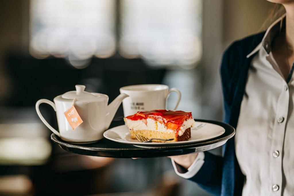 a person holding a plate with a piece of cake and a cup at Seaside 43 in Sankt Peter-Ording