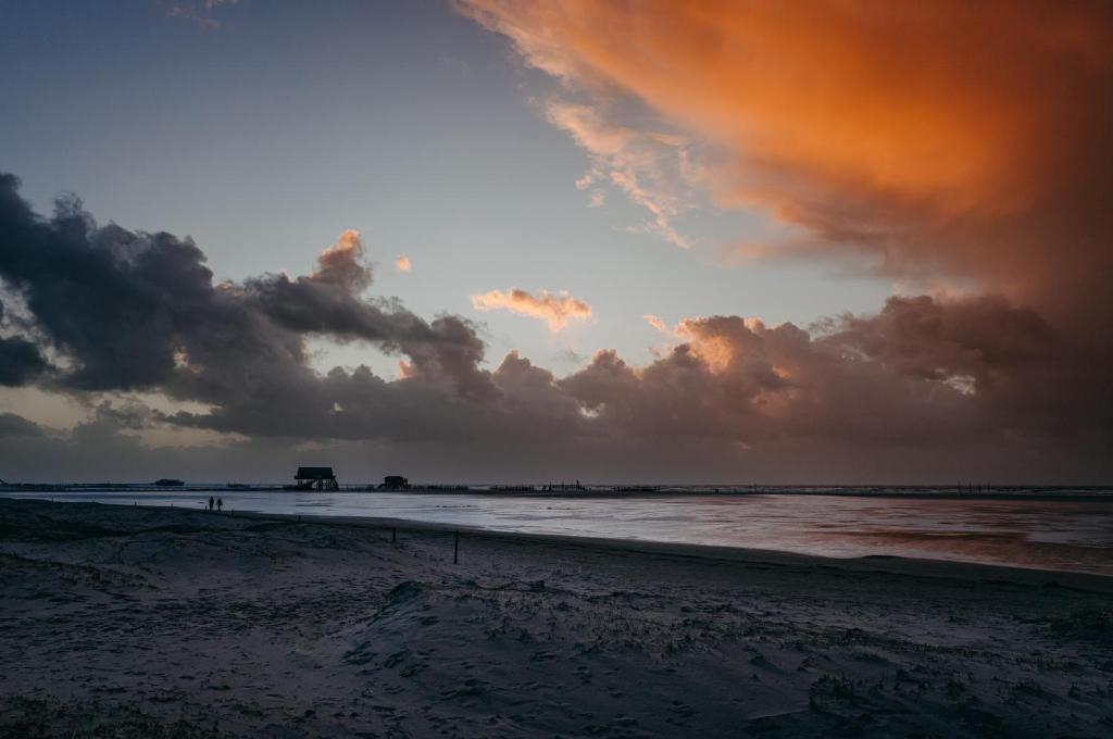 a beach with a cloudy sky and the ocean at Seaside 43 in Sankt Peter-Ording