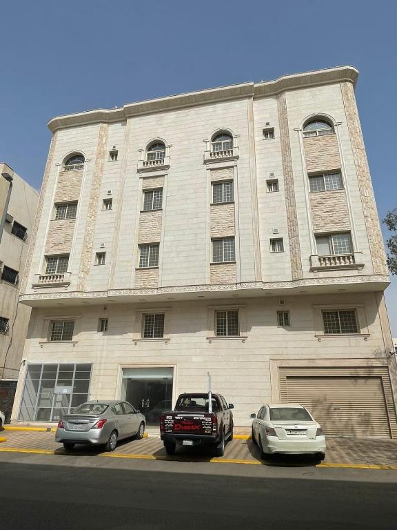 two cars parked in a parking lot in front of a building at المهاجرين فرع الحزام in Medina