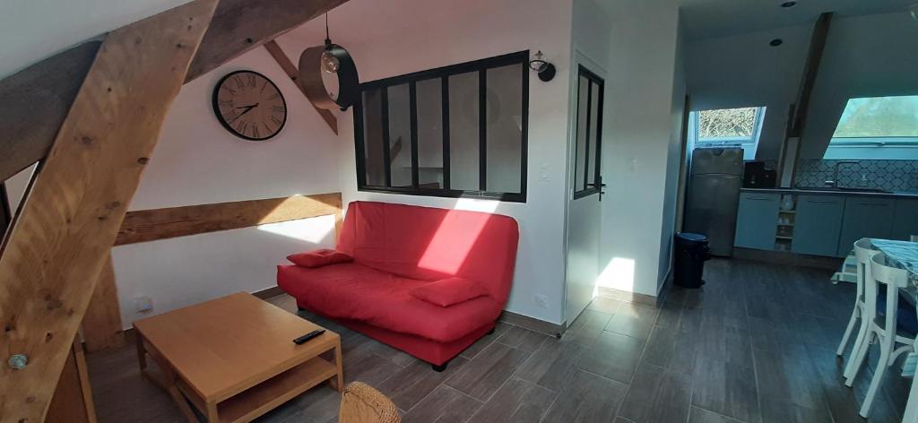 - un salon avec une chaise rouge et un réveil dans l'établissement 14 Ter Les Gîtes Bigoudens, à Plonéour-Lanvern