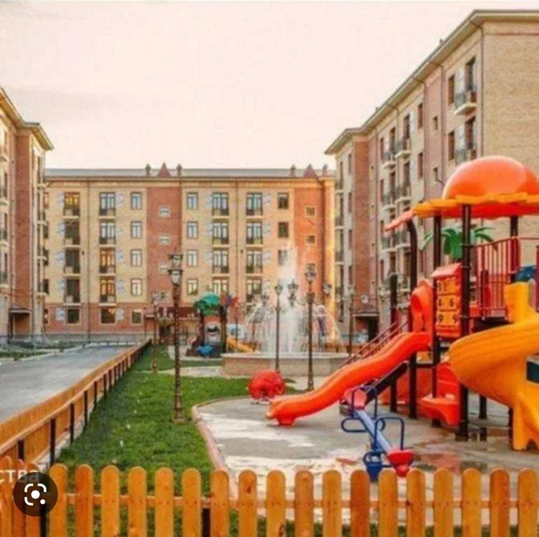 un parque infantil con un tobogán frente a un edificio en LUXURIOUS ACCOMMODATION IN 2BR APARTMENT, IN A SECURED AREA WITH COMFORTABLE DISTANCE TO R/W STATION, AIRPORT AND CITY CENTER. en Tashkent